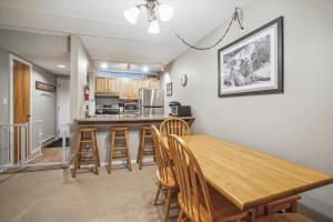 uma cozinha e sala de jantar com uma mesa de madeira e cadeiras em Pinnacle E08 em Killington