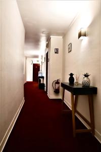 a long hallway with a red carpet and a table at Hôtel De La Loge in Perpignan