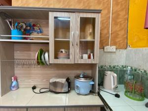 a kitchen with a cupboard with dishes and a toaster at Homestay Taman Maktab Pengkalan Chepa in Pengkalan Cepa