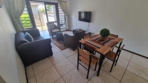 a living room with a table and a couch at Self Catering. walking distance to beach. in Uvongo Beach