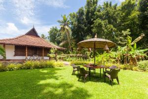 a table and chairs with an umbrella in a yard at StayVista at La Riva Heritage Villa with Bicycle in Alleppey