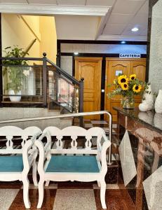 two white benches sitting in a lobby with flowers at Hotel Reyesol in Fuengirola