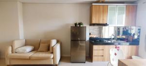 a kitchen with a couch and a refrigerator in a room at Vast! Metro Park Manhattan 2BR in Jakarta