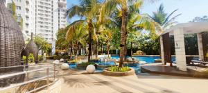 a resort with a pool and palm trees and buildings at Vast! Metro Park Manhattan 2BR in Jakarta