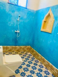 y baño azul con aseo y ducha. en Nakupenda House en Jambiani