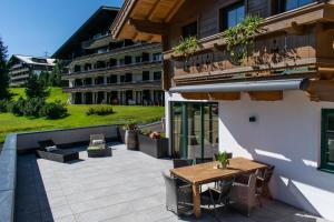 a patio with a wooden table and chairs and a building at Weinzeit Chalet & Appartements in Königsleiten