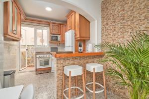 una cocina con armarios de madera y taburetes blancos en Soleada Casa en Nerja, en Nerja