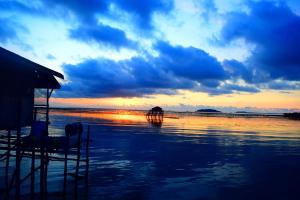 einen Sonnenuntergang am Strand mit zwei Tieren im Wasser in der Unterkunft Kelong Bintan in Teluk Bakau