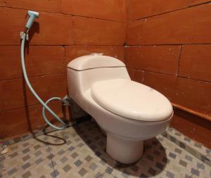 ein Bad mit einem weißen WC in einer Wand in der Unterkunft OYO 93121 Abi Bungalow & Hostel in Pawenang