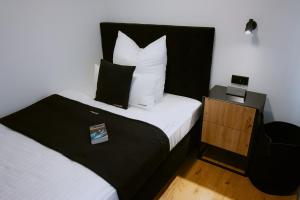 Schlafzimmer mit einem Bett mit weißer Bettwäsche und Kissen in der Unterkunft KOCAK - Exklusives Apartment in Zentrumsnähe in Reutlingen