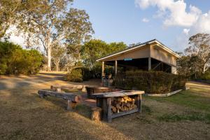 a building with a fire grill in a field at Barrington Riverside Cottages in Barrington