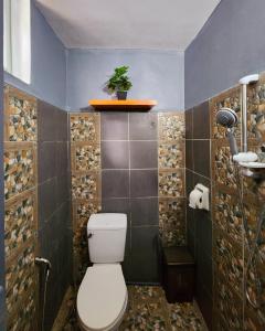 a bathroom with a toilet and a tile wall at Uno Dus Tourist Inn in Itaytay