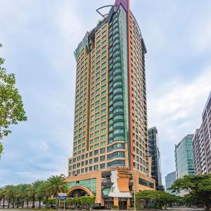 a tall building in a city with palm trees at Vivere Hotel and Resorts in Manila