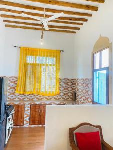 a living room with a yellow curtain and a window at Nakupenda House in Jambiani