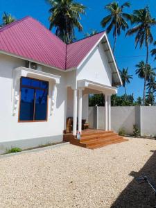 a small white house with a pink roof at Nakupenda House in Jambiani