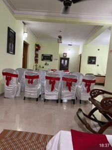 a room with a long table with white chairs and red bows at Urban Rose Homestay in Kannur