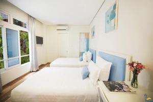 een slaapkamer met 2 bedden en een tafel met bloemen bij Cọ Xanh Hotel in Da Nang