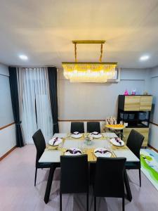 une salle à manger avec une table, des chaises et un lustre dans l'établissement KITJA MY HOME, à Hat Yai