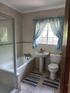 a bathroom with a toilet and a tub and a sink at Charming Randburg Accommodation near the Olivedale Clinic in Sandton