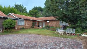 a brick house with a table and chairs in the yard at Charming Randburg Accommodation near the Olivedale Clinic in Sandton