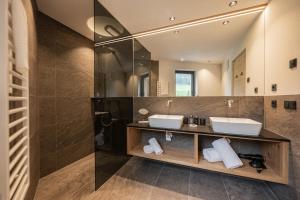 a bathroom with two sinks and a mirror at Vista Chalets Sexten in Sesto