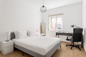 um quarto branco com uma cama, uma secretária e um computador em Altido Central & spacious apt in Porto no Porto