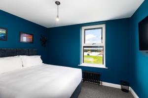 a blue bedroom with a bed and a window at 23 Trafalgar Square with hot tub and cinema in Scarborough