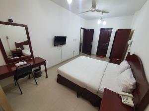 a bedroom with a bed and a mirror and a desk at Alreef Hotel Suits in Muscat +8 photos