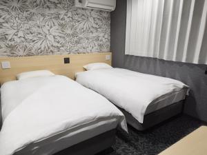 zwei Betten in einem Zimmer mit einem Wandbild in der Unterkunft Hotel Shin-Imamiya in Osaka