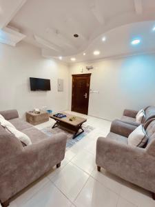 a living room with two couches and a tv at فلورز سويتس in Yanbu
