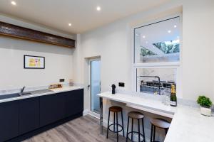 a kitchen with a sink and a counter with stools at 23 Trafalgar Square with hot tub and cinema in Scarborough