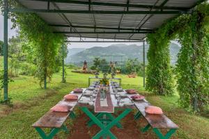 a long picnic table in a field with at SaffronStays Le Farm By The Lake In Kamshet in Somavadi