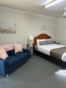 1 dormitorio con 1 cama y 1 sofá azul en Murgon Motor Inn, en Murgon