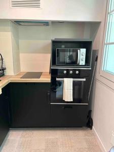 une cuisine avec un four micro-ondes sur une armoire noire dans l'établissement Spacieux T3 Métro Saint Cyprien / 4-8 personnes, à Toulouse