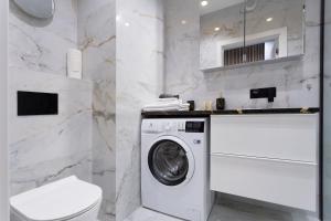 a white bathroom with a washing machine and a toilet at AVRA Residence II Stare Miasto in Gdańsk