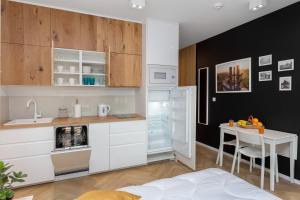 a kitchen with white cabinets and a table and a refrigerator at AVRA Residence II Stare Miasto in Gdańsk