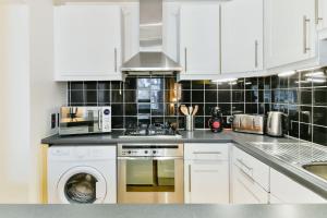 a kitchen with white cabinets and a stove top oven at Knightsbridge Stylish Two Bedroom Apartment in London