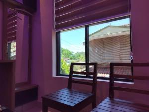 um quarto roxo com uma cadeira e uma janela em IvyArk Residency em Pinangode