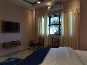 um quarto com uma cama, uma janela e uma televisão em IvyArk Residency em Pinangode