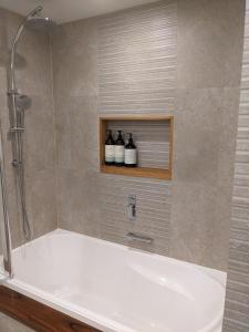 a bathroom with a tub and a shower with three bottles at BestView St Kilda Spectacular Sunset Hideaway - boutique self-contained luxury apartment in Melbourne