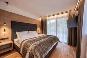 a bedroom with a large bed and a large window at Vista Chalets Sexten in Sesto