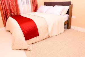 a bed with a red and white blanket on it at The Lotus Stay-in at Paradise Apartments, Embu in Embu