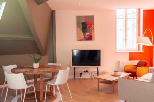 a living room with a table and a television at Suite Germain - 4 pers. in Charleville-Mézières