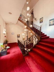 escalera con alfombra roja y lámpara de araña en Hôtel De La Loge en Perpiñán