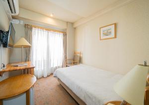 una camera d'albergo con letto, scrivania e finestra di Saka no Hotel Tretio Ochanomizu a Tokyo