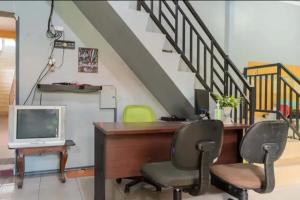 um escritório com uma secretária e duas cadeiras e um computador em OYO 93071 Home Stay Kembar Syariah em Binjai
