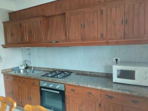 a kitchen with wooden cabinets and a stove and a microwave at Piso en Grove in O Grove