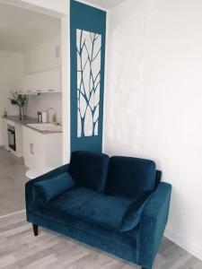 a blue couch in a living room with a kitchen at Le belvédère-centre ville in Belfort