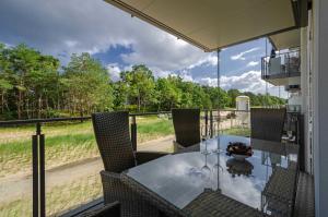 een glazen tafel en stoelen op een balkon met uitzicht op een veld bij FeWo Prora - Moin in Binz