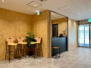 a lobby with two bar stools and a plant at CHECKinn Osaka Shinimamiya in Osaka